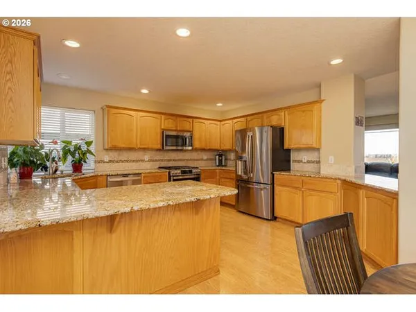 a kitchen with stainless steel appliances granite countertop a refrigerator a stove and a sink