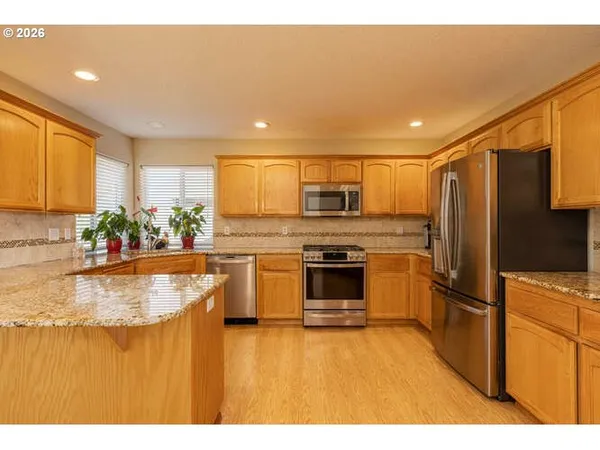 a kitchen with stainless steel appliances granite countertop a refrigerator a stove and a sink