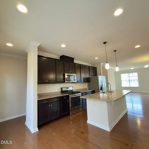a kitchen with stainless steel appliances granite countertop a refrigerator a sink a stove and a wooden floors