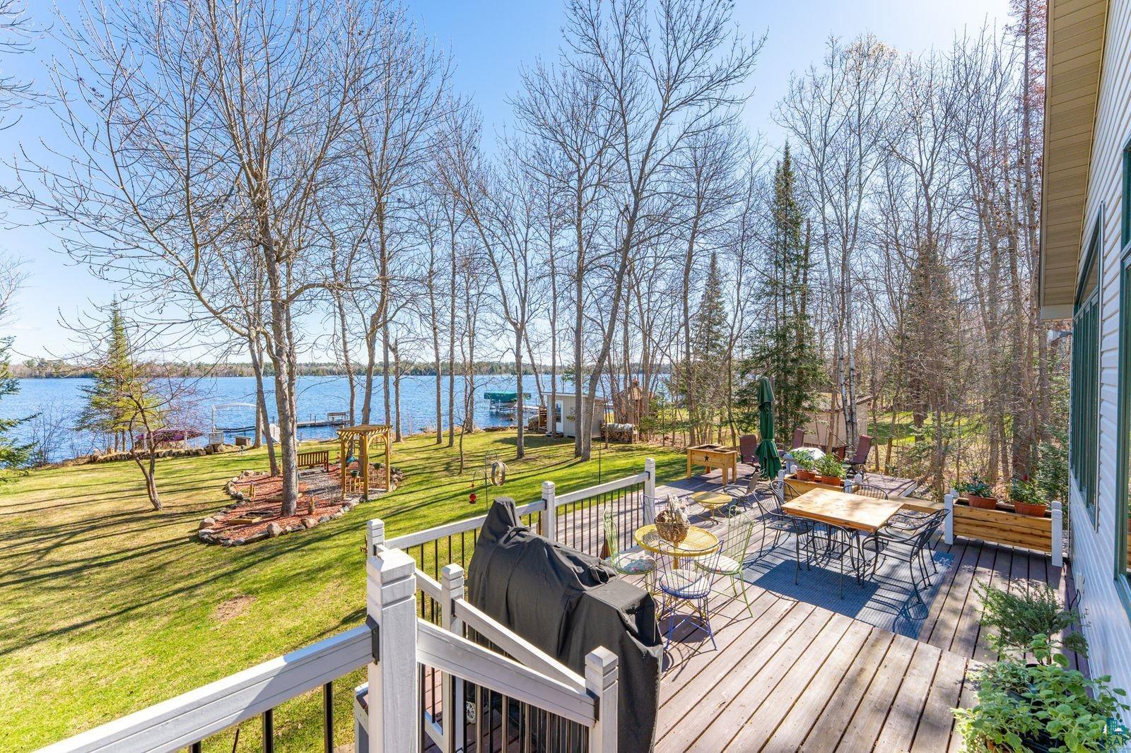 4452 Moccasin Point Road Tower, MN 55790 - Photo 27 of 44 Expansive wooden deck with white railings overlooks a manicured lawn and large body of water