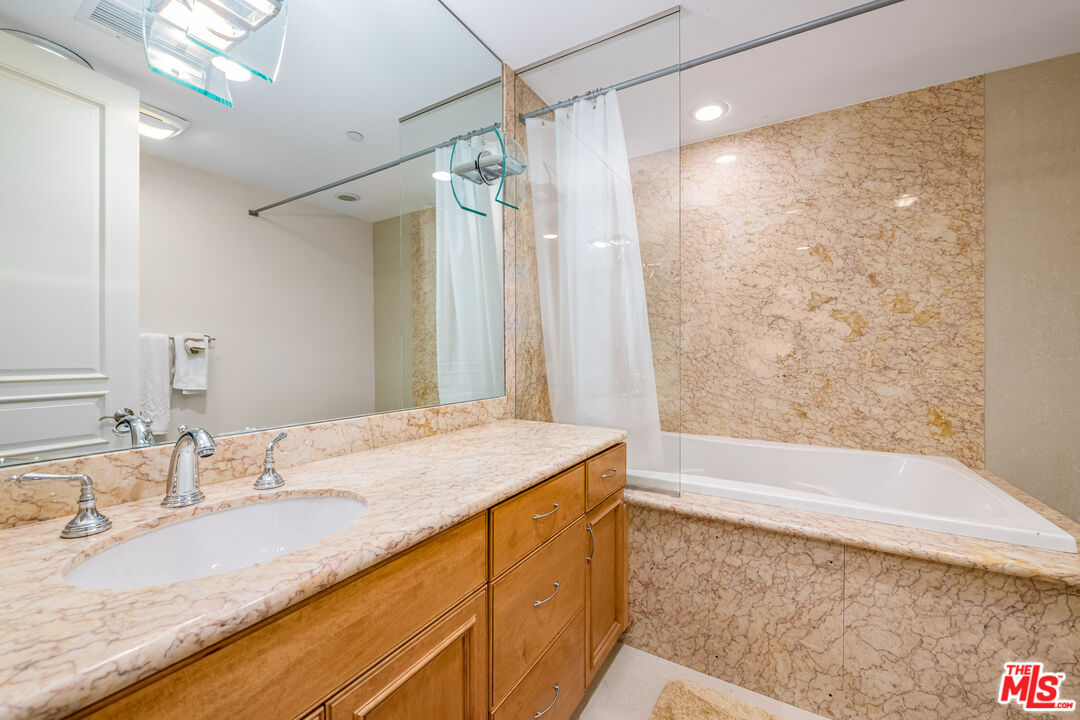 936 Kenfield Avenue Los Angeles, CA 90049 - Photo 17 of 30 a bathroom with a granite countertop sink a mirror and a bathtub