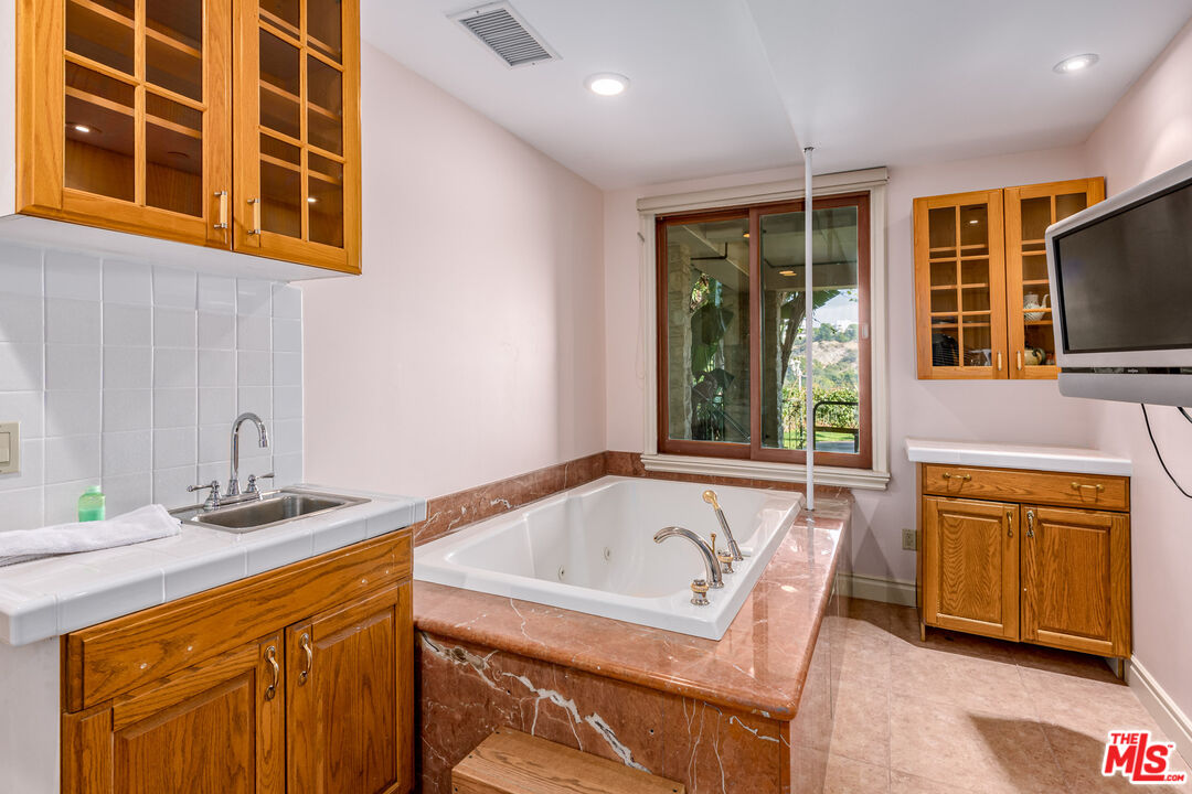 936 Kenfield Avenue Los Angeles, CA 90049 - Photo 22 of 30 a bathroom with a tub sink and mirror