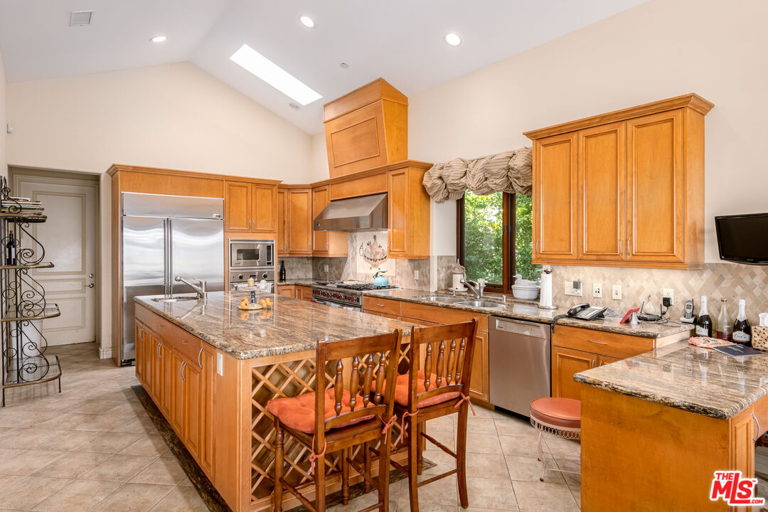 936 Kenfield Avenue Los Angeles, CA 90049 - Photo 8 of 30 a kitchen with stainless steel appliances granite countertop a stove a sink and a refrigerator