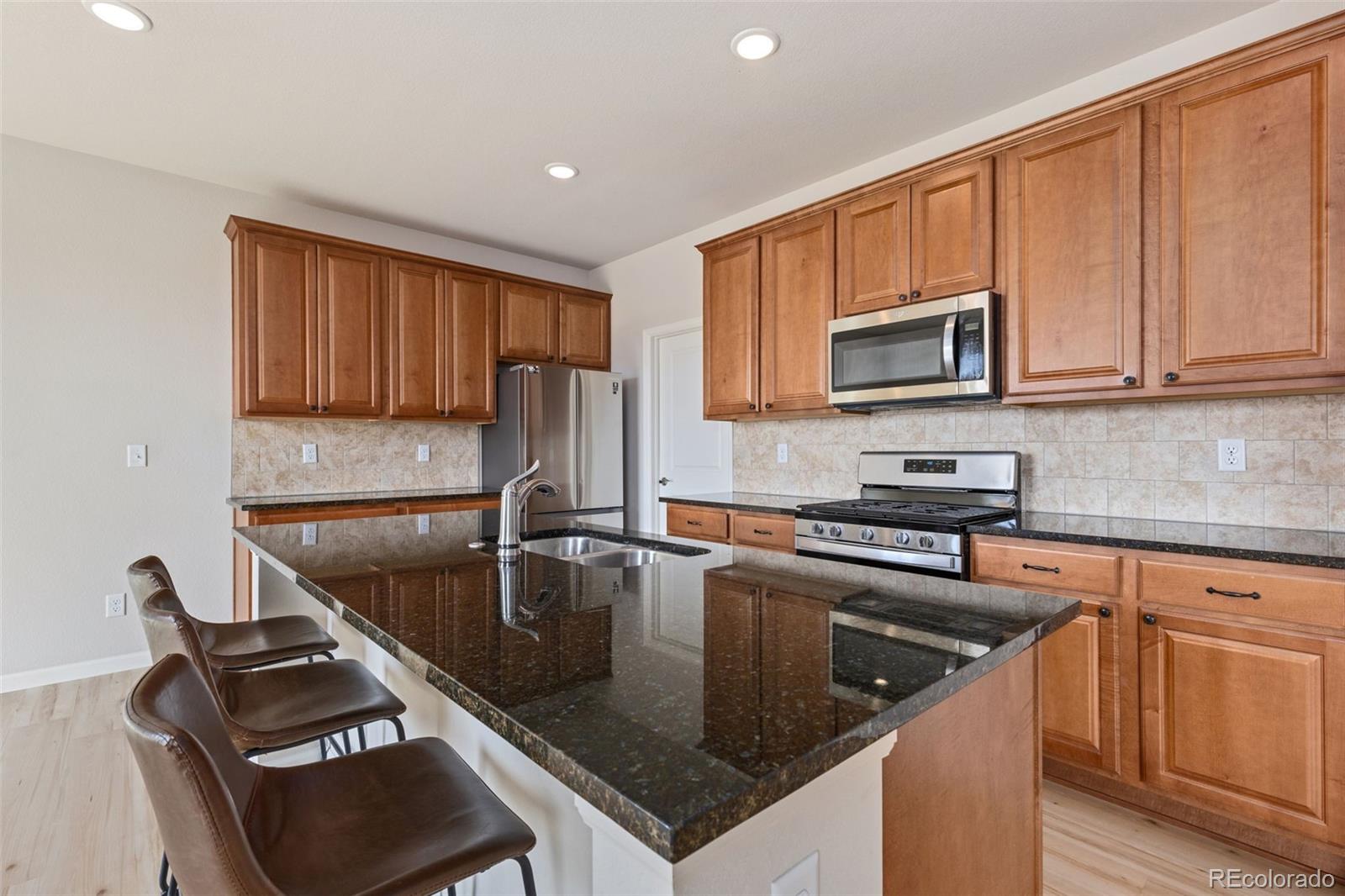 2771 Big Empty Place Berthoud, CO 80513 - Photo 7 of 25 a kitchen with kitchen island granite countertop a sink stove and microwave