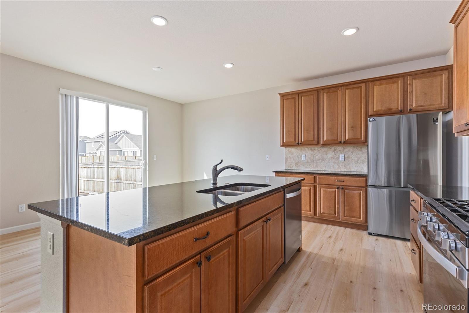 2771 Big Empty Place Berthoud, CO 80513 - Photo 8 of 25 a kitchen with stainless steel appliances granite countertop a refrigerator a sink dishwasher a stove and white countertops with wooden floor