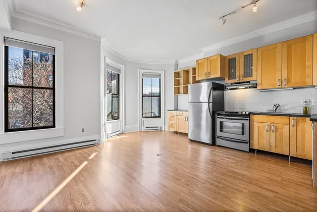a kitchen with granite countertop a refrigerator and wooden floors
