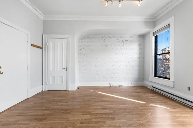 a view of an empty room with window and wooden floor