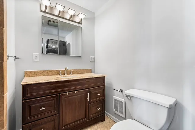 a bathroom with a granite countertop toilet sink and mirror