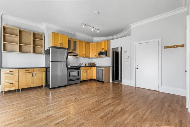 a kitchen with stainless steel appliances a refrigerator and wooden floor