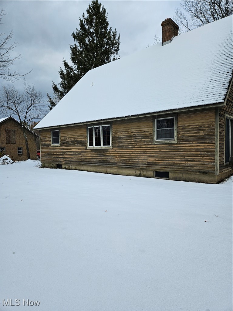 View of snowy exterior with a chimney