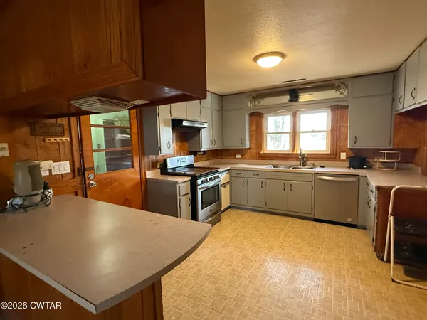 a view of kitchen with stainless steel appliances granite countertop a sink and cabinets