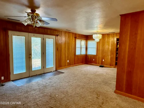 a view of a livingroom with a chandelier fan and windows