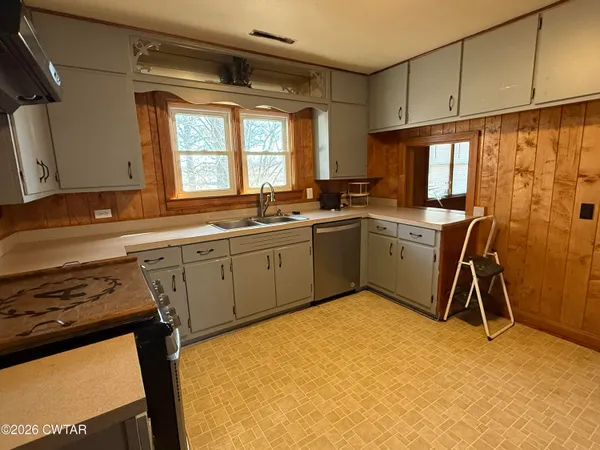 a kitchen with a sink a stove top oven a cabinetry and chairs