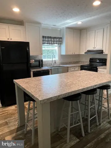 a kitchen with granite countertop a table chairs microwave and cabinets