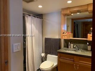 1688 West Avenue, Unit 405 Miami Beach, FL 33139 - Photo 10 of 23 a bathroom with a granite countertop sink toilet a mirror a vanity and shower