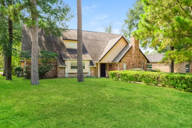 a view of a house next to a big yard and large trees