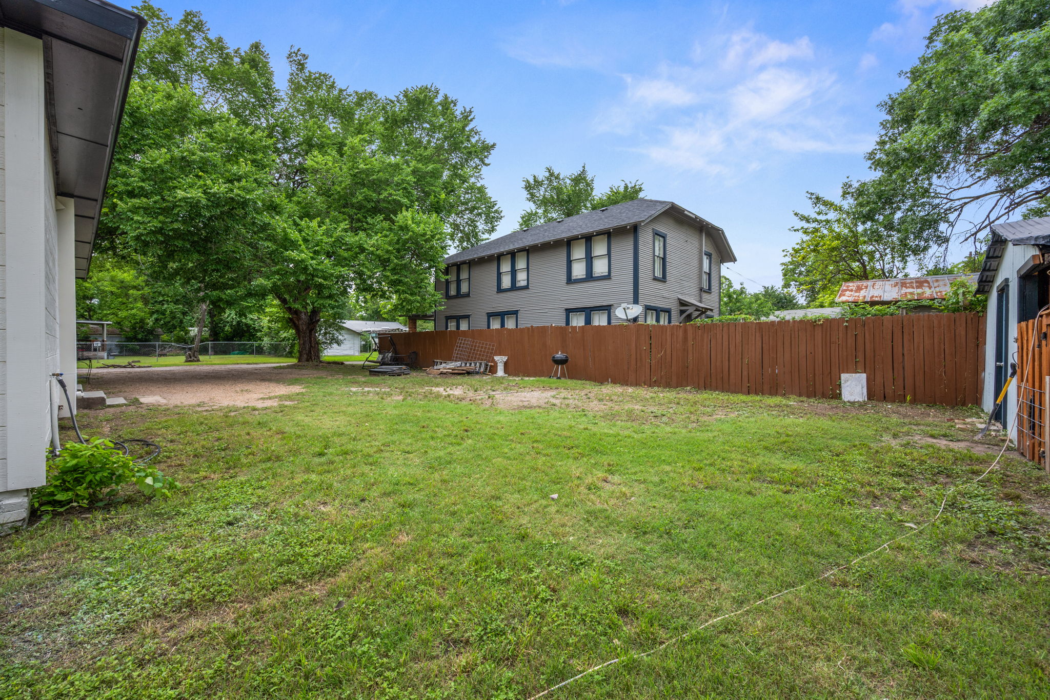 602 East 6th Street Cameron, TX 76520 - Photo 36 of 40 Spacious backyard with a mix of grass and natural ground cover, featuring a privacy fence