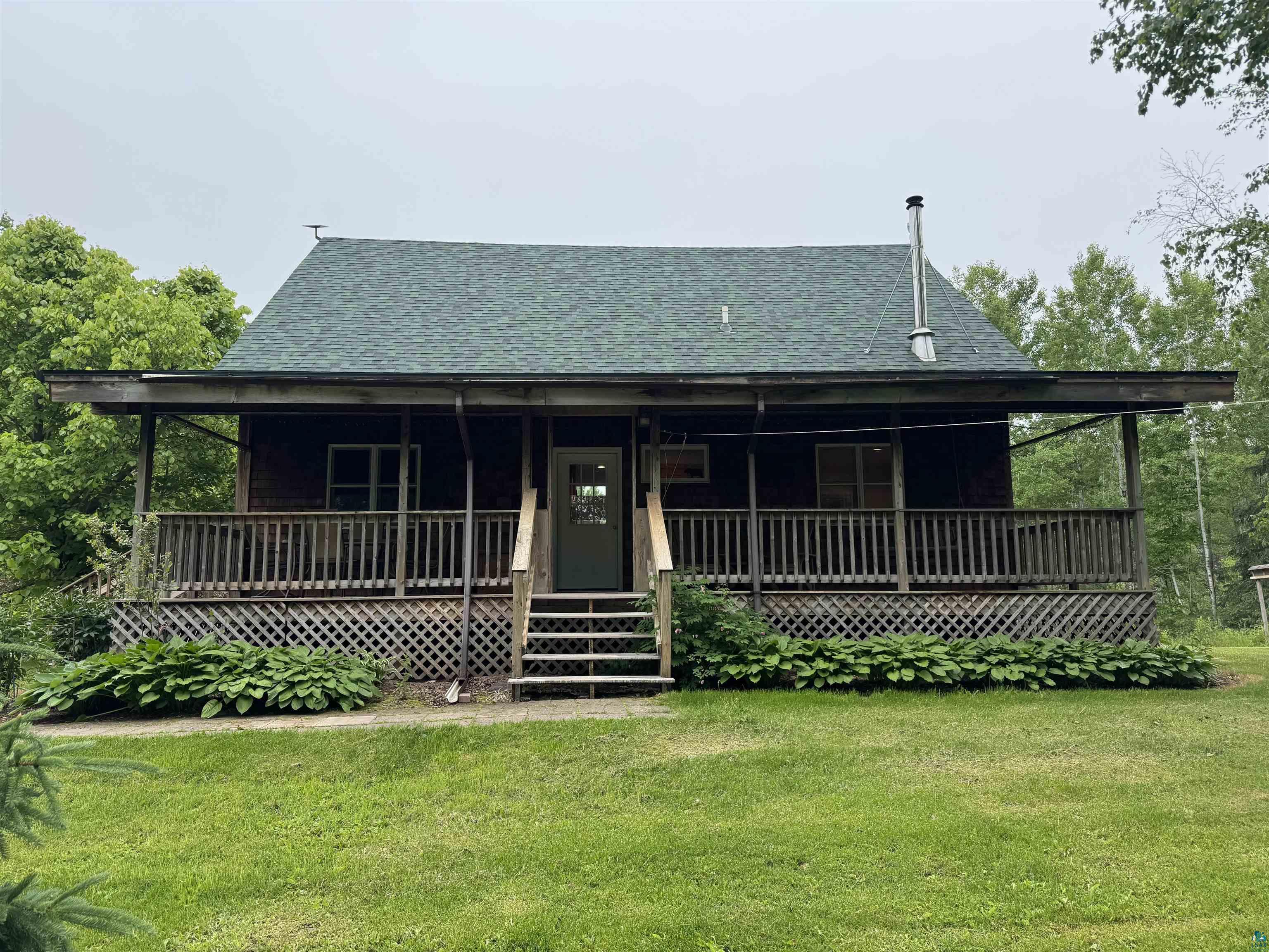 1745 Becks Road Maple, WI 54854 - Photo 3 of 46 Wood-sided home featuring a covered front porch with wood railings and lattice skirting
