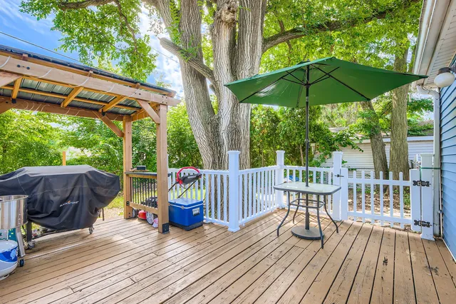 a patio with wooden floor a yard a table and chairs