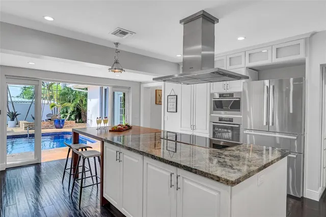 a kitchen with stainless steel appliances granite countertop a sink and wooden floors