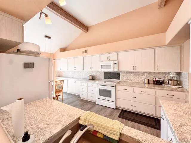 a kitchen with granite countertop white cabinets and white appliances