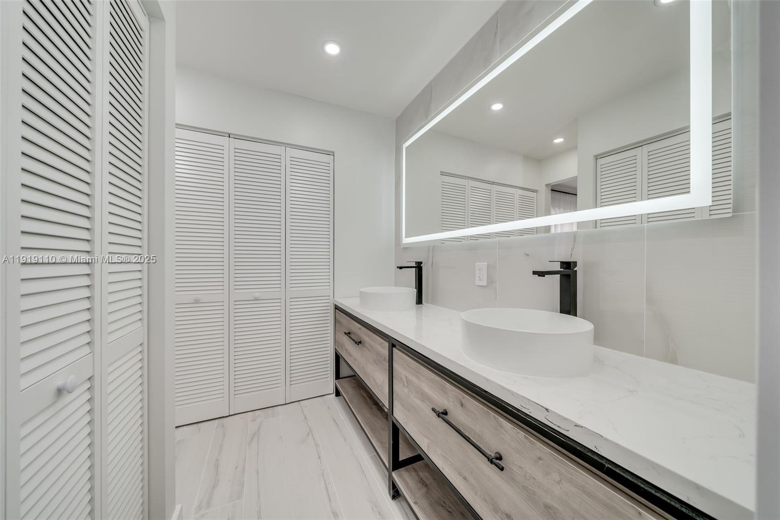 4155 Southwest 66th Terrace, Unit 104 Davie, FL 33314 - Photo 19 of 25 a bathroom with a double vanity sink and mirror