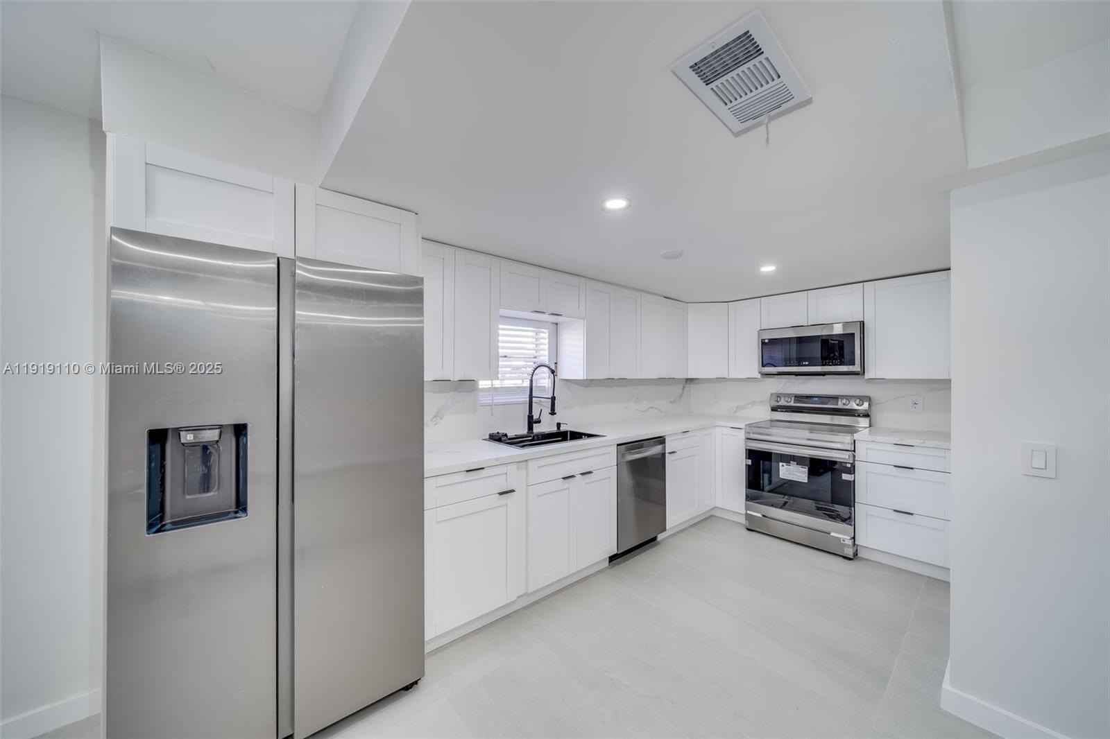 4155 Southwest 66th Terrace, Unit 104 Davie, FL 33314 - Photo 9 of 25 a kitchen with white cabinets and stainless steel appliances