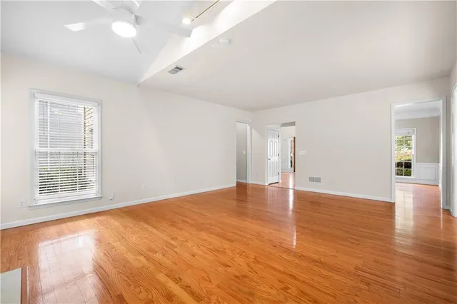 a view of an empty room with wooden floor and a window