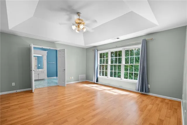 a view of an empty room with a window and wooden floor