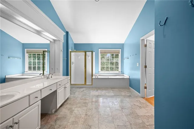 a spacious bathroom with a granite countertop sink a mirror and a bathtub next to a window