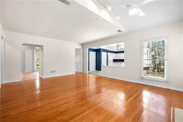 an empty room with wooden floor and windows