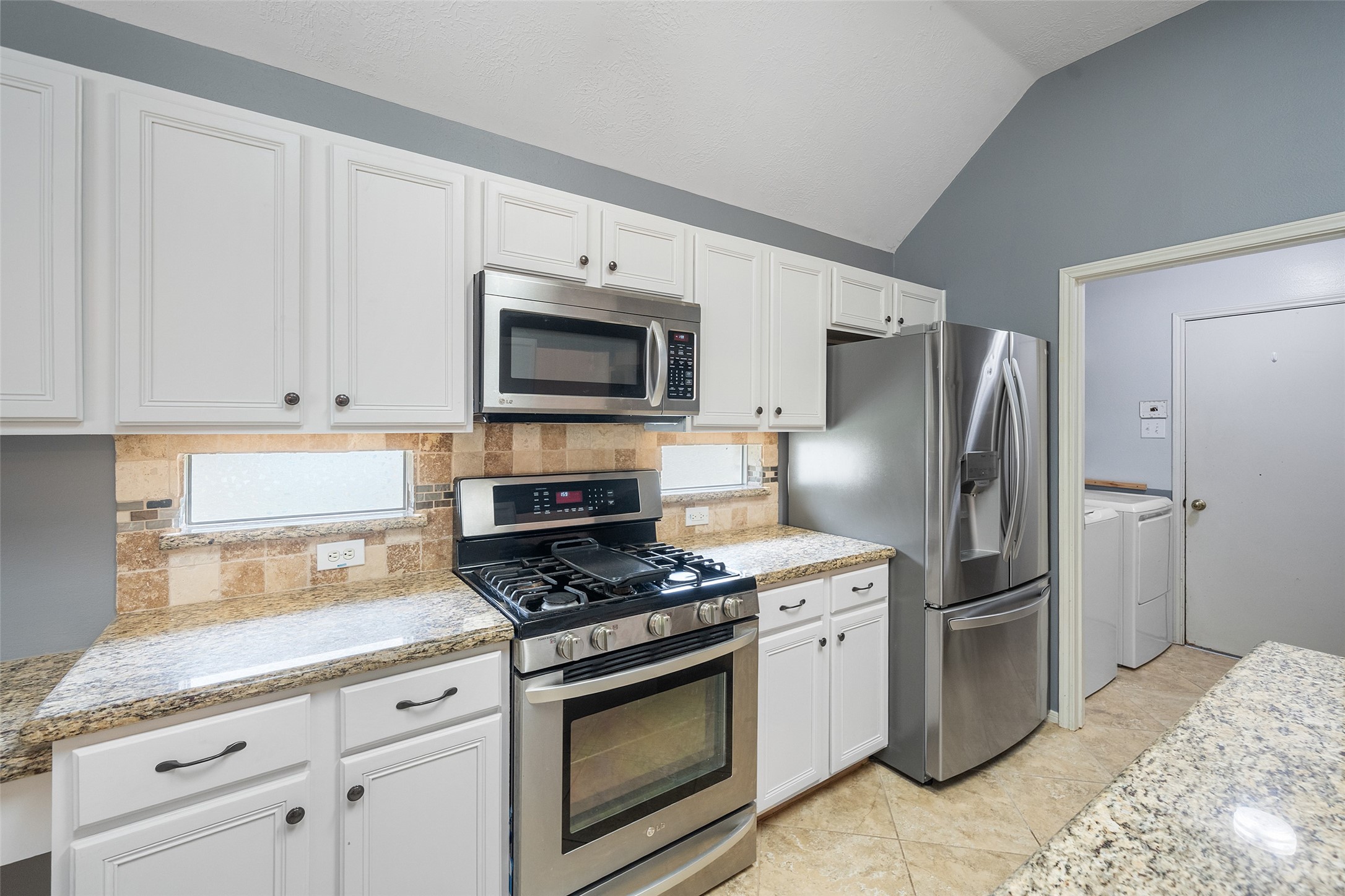 19718 Teller Boulevard Spring, TX 77388 - Photo 18 of 47 a kitchen with granite countertop a refrigerator stove and microwave