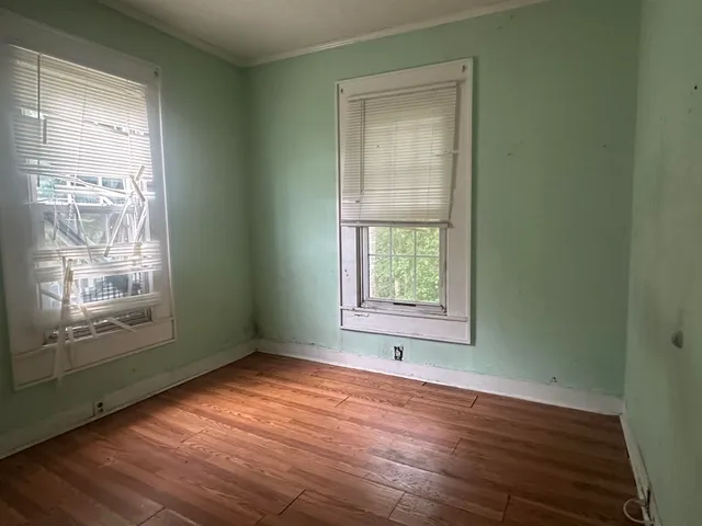 an empty room with wooden floor and windows