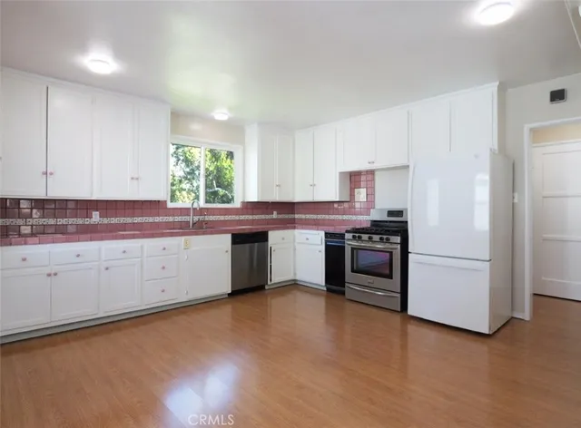 a kitchen with stainless steel appliances white cabinets a sink and a stove