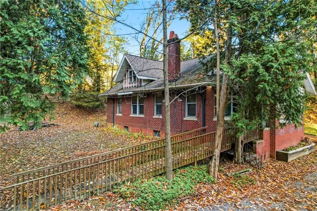 a view of a house with a large tree and wooden fence