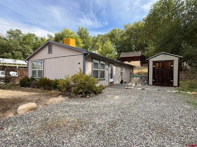 a view of a house with a yard and large tree