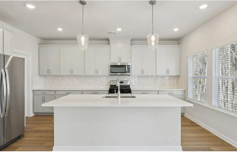 7231 Lyric Street Fairburn, GA 30213 - Photo 4 of 12 a kitchen with kitchen island white cabinets and stainless steel appliances