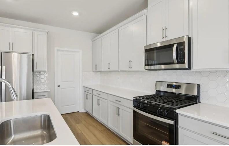 7231 Lyric Street Fairburn, GA 30213 - Photo 6 of 12 a kitchen with stainless steel appliances white cabinets and a stove top oven