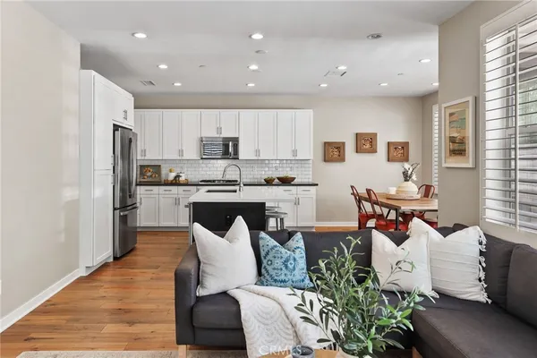 a living room with stainless steel appliances furniture and a kitchen