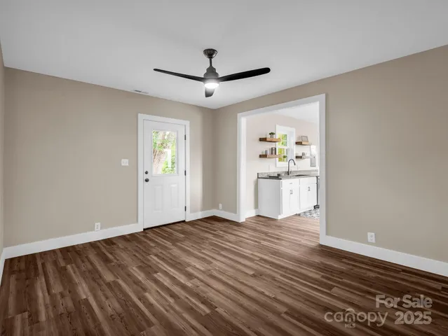 a view of an empty room with window and wooden floor