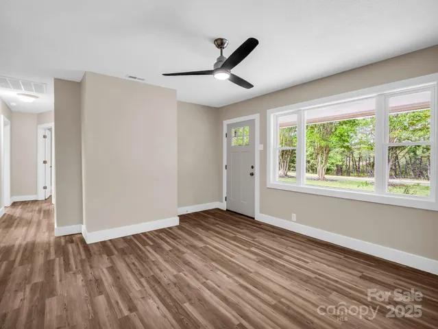 a view of empty room with wooden floor and fan