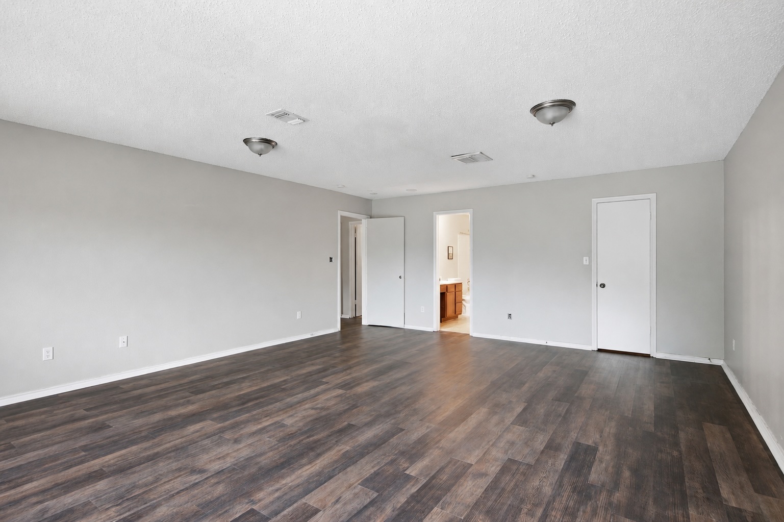 7900 Rosenberry Drive Austin, TX 78747 - Photo 18 of 27 A spacious room featuring contemporary wood plank flooring, leading to an adjacent bathroom.