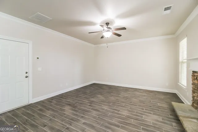 a view of empty room with wooden floor and fan