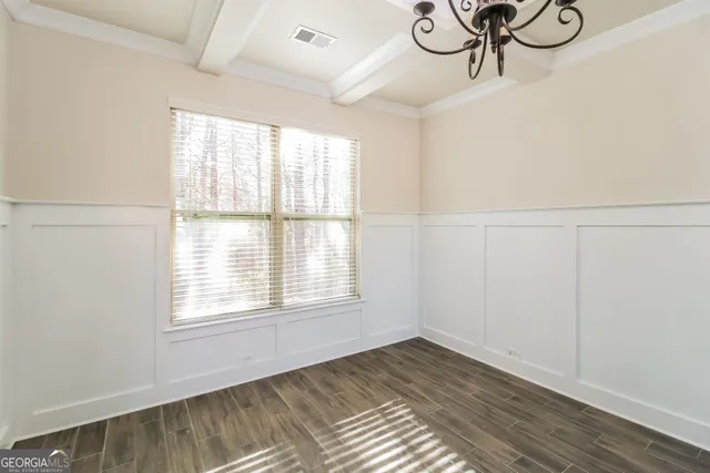 a view of an empty room with a window and wooden floor