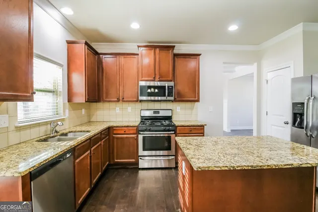 a kitchen with stainless steel appliances granite countertop a stove a sink and a refrigerator
