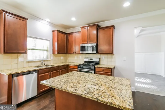 a kitchen with stainless steel appliances granite countertop wooden cabinets and a stove top oven
