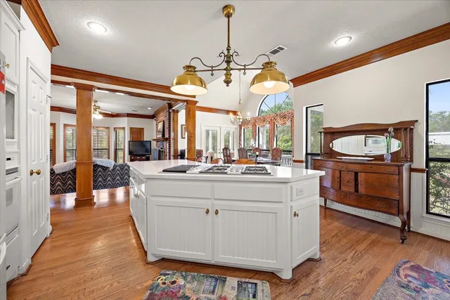 a large white kitchen with a large island oven a stove and a wooden floors