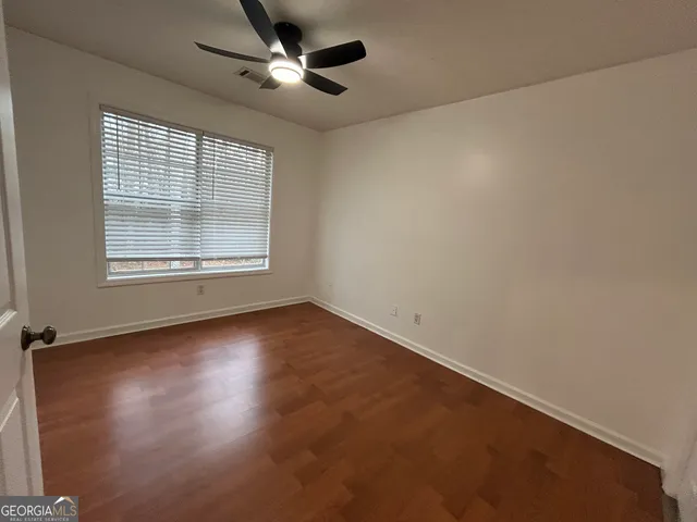 an empty room with a window and a fan