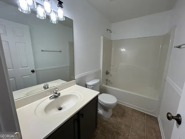 an empty room with wooden floor chandelier fan and windows