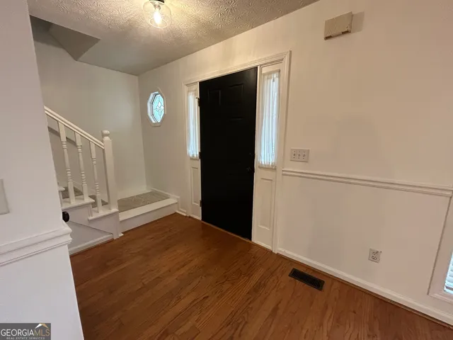 an empty room with wooden floor fireplace and windows